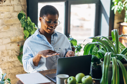 Cheerful healthy African American woman with laptop at home or in modern green office. Concept of video call, freelance job, studying remotely, learning, teaching languages, international education