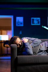 Sad man lounged on couch feeling heartbroken while watching tragic movie on streaming service. Person laying down hugging pillow seeing TV show favorite character dying, looking for emotional comfort