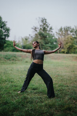 Obraz premium A young girl dances in the park, showcasing graceful movements amidst a green natural setting, embodying freedom and joy.