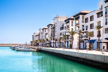 Obraz premium Agadir Marina with luxury apartments, boats in harbor, shops and restaurants. Popular tourist destination in Moroccan seaside resort on shore of Atlantic ocean in Africa