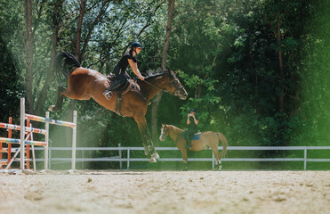 A horse rider jumping over an obstacle in an outdoor equestrian competition with another person...