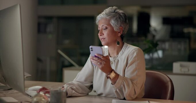 Business, woman and smartphone at night in office with computer for task and project deadline. Mature person, typing and online for webdesign for company with technology, overtime and website layout.