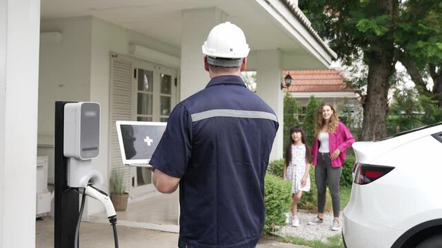 Qualified technician working on home EV charging station installation, making troubleshooting and configuration setup on charging system with laptop for EV at home. Fastidious
