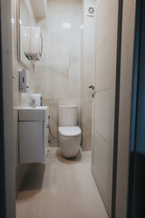 This bathroom features sophisticated marble tiles with a striking pattern, complemented by sleek white fixtures, mirror, and well-organized amenities.