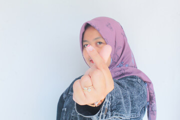 Portrait of a young woman in a stylish purple hijab putting both her hands together in a love sign in front of her face.