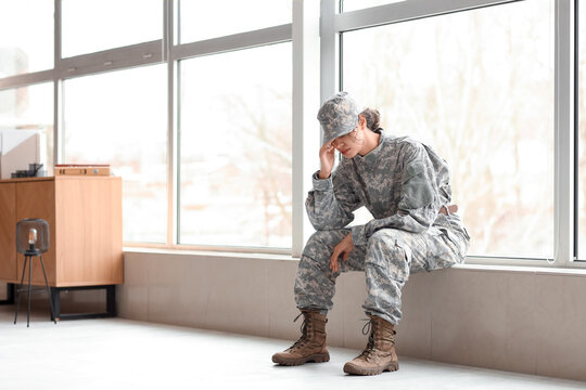 Sad female African-American soldier sitting on windowsill at headquarters