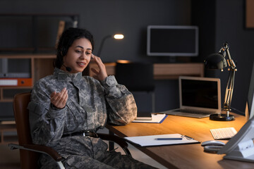 Female African-American soldier with headset working in headquarters at night