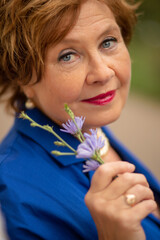 Fototapeta premium Woman with short curly hair holding purple flowers outdoors in a