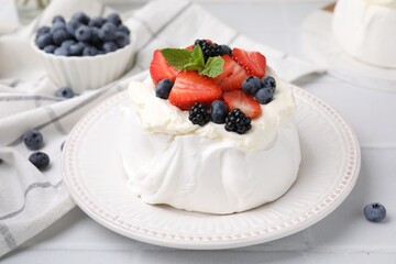 Pavlova cake (meringue dessert) with whipped cream, fresh berries and mint on white table, closeup