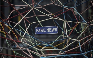 fake news sign in the middle of a tangled web of thin ropes symbolizing disinformation spread - misinformation, media manipulation, social influence