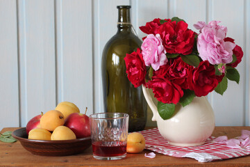 wine, flowers and fruits. table setting. summer rural still life. scarlet roses.