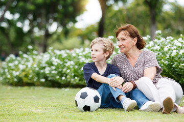 Grandchild and grandmother relaxing at park or grass field.