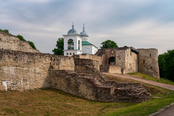 View of the wall of the Izborsk fortress, the Nikolsky Gate and St. Nicholas (Nikolsky) Cathedral (XIV-XVII century) on a sunny summer day, Izborsk, Pskov region, Russia