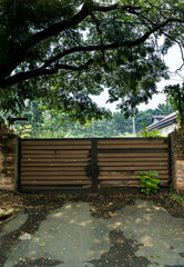 An old weathered wooden garage  entrance gate with fallen rotting leaves in the foreground.  