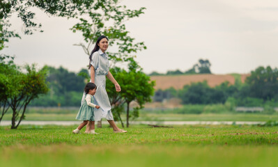 mother walking with her crying toddler baby girl on grass field in park