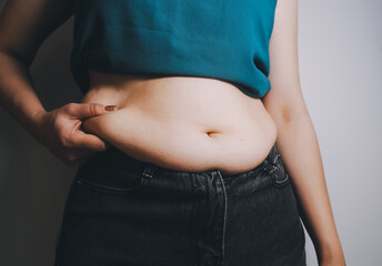 Naklejka premium fat woman, fat belly, chubby, obese woman hand holding excessive belly fat with measure tape, woman diet lifestyle concept