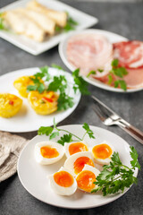 Boiled eggs and Egg muffins ( bites) with parsley leaves  in a plate on a dark background.