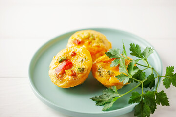 Egg muffins ( bites) and parsley leaves  in a plate on a gray background.