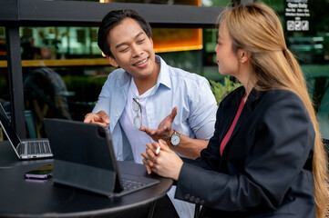 A smart Asian businessman is having an informal meeting with his colleague at a coffee shop.