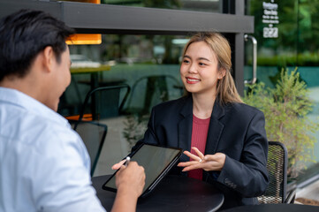 A beautiful Asian businesswoman is having an informal meeting with her client at a coffee shop.