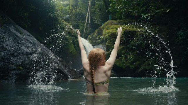 Young woman enjoying a tropical rainforest waterfall in the jungle 