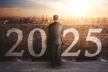 Businessman looking at a port over a wall with 2025 numbers written on it - Business future...