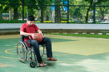 Upset man in wheelchair with ball on sports ground