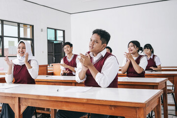 Multiethnic Asian Students Clapping Hands In Classroom