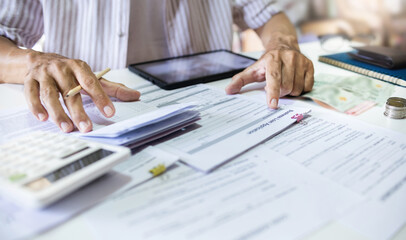 Asian man review business loan application and checking funds in passbook before apply for loan approval to start new business