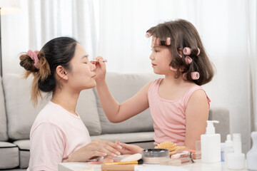 Happy children makeup and make hair styles for mother. Girl applying makeup. Advertisement, lifestyle , cosmetics, makeup accessories, beauty activity, beautician, talent, love beauty