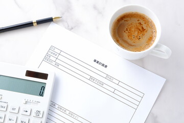 新規事業の立ち上げに先立ち、コーヒーを飲みながら、事業計画書を作成している起業家のイメージ
