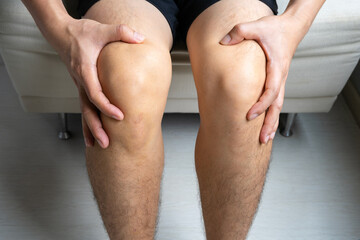 Man with knee pain, he puts his hand on his knee, pain point from osteoarthritis and...