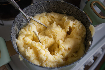 pot of creamy mashed potatoes sits invitingly, ready to be savored. The perforated potato masher leans against it, symbolizing the art of comfort cooking and homely meals