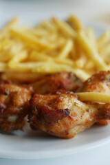 Delicious Chicken Wings with crispy French Fries, beautifully presented on a White Plate