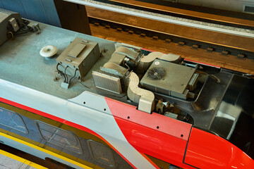 Fototapeta premium View of roof of new red and grey electric train showing ventilation system. Close-up details of the locomotive on railway station. Railroad transport