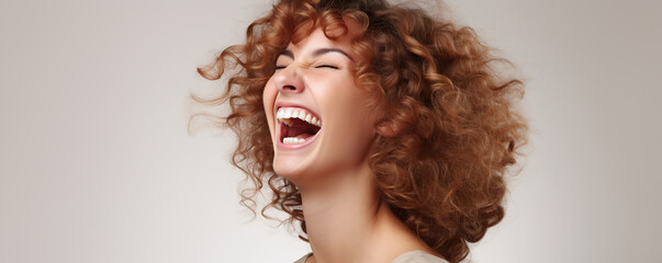 Fototapeta premium A joyful young woman with curly hair laughing