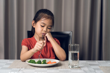 Little cute kid girl refusing to eat healthy vegetables. Children do not like to eat vegetables.