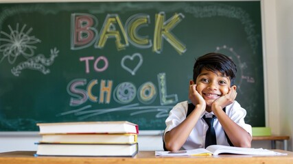 Excited Indian School Boy Smiling in Front of Back to School Chalkboard