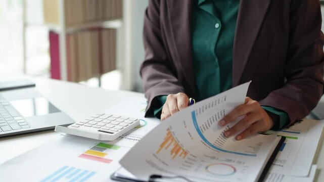 Asian business woman working using laptop computer, marketing report with calculator document on table Planning to analyze financial reports Investing in an online business plan, e-commerce.