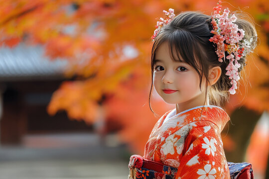 Young girl smiles sweetly while celebrating shichi go san at a local shrine. She is dressed in a vibrant red kimono with her hair done up in a traditional style