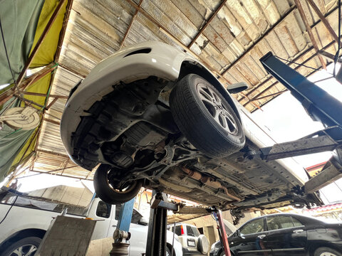 Car being serviced in garage, showcasing undercarriage and tires. scene conveys sense of maintenance and repair.