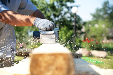 a carpenter works with an electric pipe on a sunny day