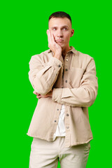 Young Man in Casual Attire Posing Thoughtfully Against a Bright Green Background