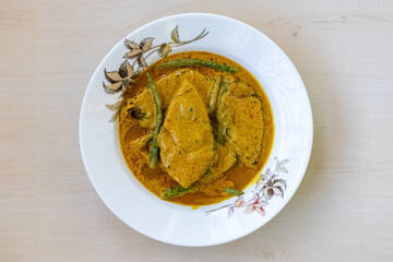 Traditional Bengali cuisine Shorshe Ilish on a white plate, cooked with mustard. This recipe is made from Hilsa fish (Tenualosa ilisha) and it is very popular in Bangladesh and West Bengal, India.