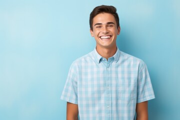 Fototapeta premium A young man is smiling and wearing a blue plaid shirt