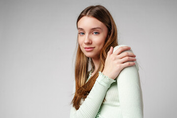 Woman in Green Cardigan and Beige Cargo Pants Poses Against a White Wall