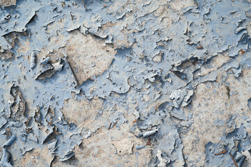 a concrete wall with old cracked flaking paint. Weathered rough painted surface with patterns of cracks and peeling.