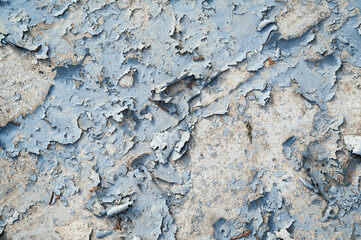 a concrete wall with old cracked flaking paint. Weathered rough painted surface with patterns of cracks and peeling.