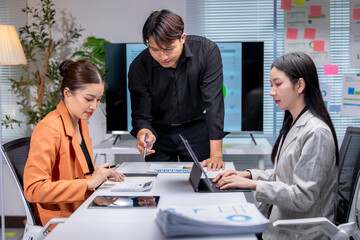 Asian business team working with financial data and using calculator in office meeting