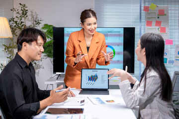 Asian businesswoman leading meeting with charts and business data on screen in office conference room
